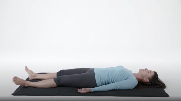 Woman lying down on the meditation mat.